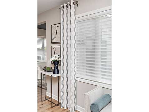A large window showcasing hanging blinds and drapery